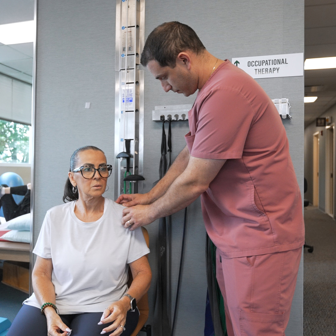 The image depicts a medical professional performing an examination on a seated woman using a blood pressure monitor.